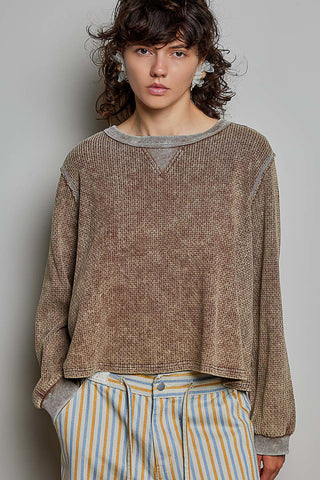 A model wearing an oversized long sleeve waffle knit top in chocolate color.
