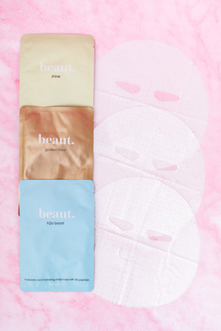 Three Beaut. sheet mask packages labeled Shine, Golden Hour, and H2O Boost on a pink background with perforated sheet masks displayed.