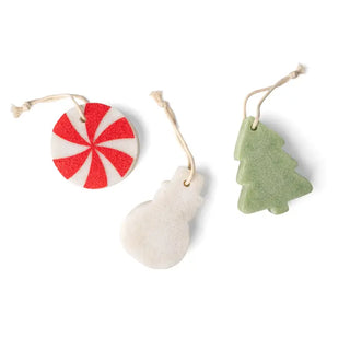 Three soap-infused sponges in shapes of a candy swirl, snowman, and Christmas tree, each with a hanging cord.