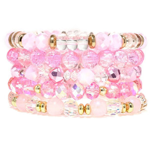 Stack of multicolor bracelets featuring faceted and smooth pink, clear, and gold beads.