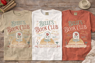 Three t-shirts with 'Belle's Book Club' design on a wooden surface.