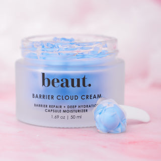 A jar of Beaut. Barrier Cloud Cream with a blue and white swirl texture and a spatula on a pink background.