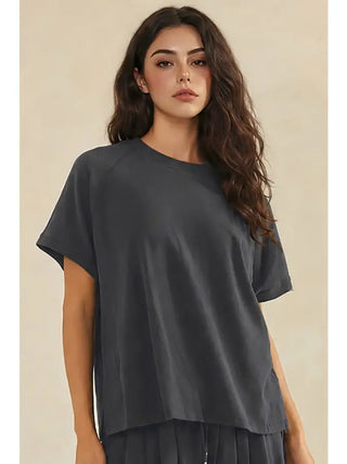 A woman wearing a relaxed crew neck raglan style short sleeve top in charcoal.