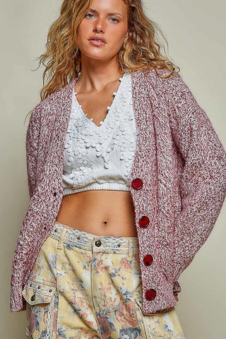 Woman wearing a ruby multi-colored cable knit cardigan with V-neck and button front.