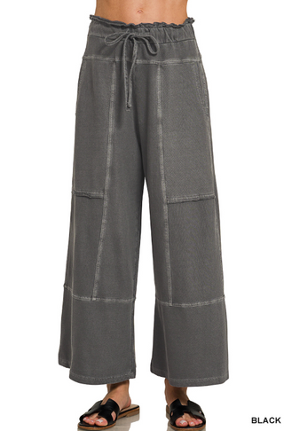Black wide leg pants with exposed seams and a drawstring waist.