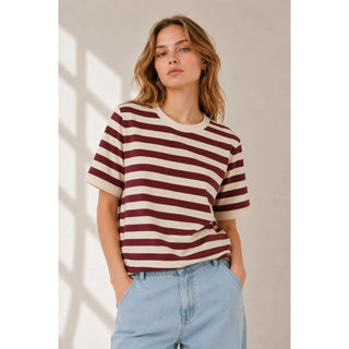 A woman wearing a dark mauve and ivory striped knit tee with short sleeves.