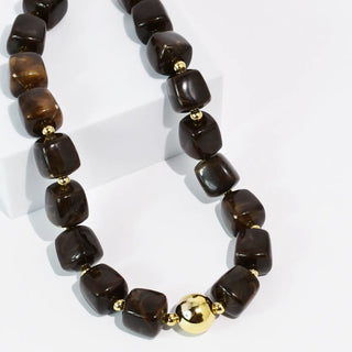 Necklace with dark polished stones and gold-tone accents.