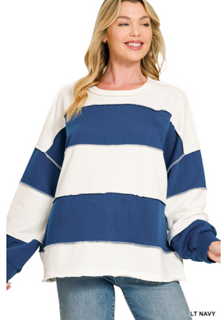 A woman wearing a light navy and white color block top with exposed seams and a relaxed fit.