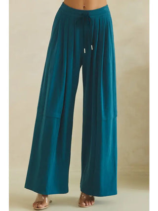 Wide-leg teal pants with adjustable drawstring waist, shown on a model.