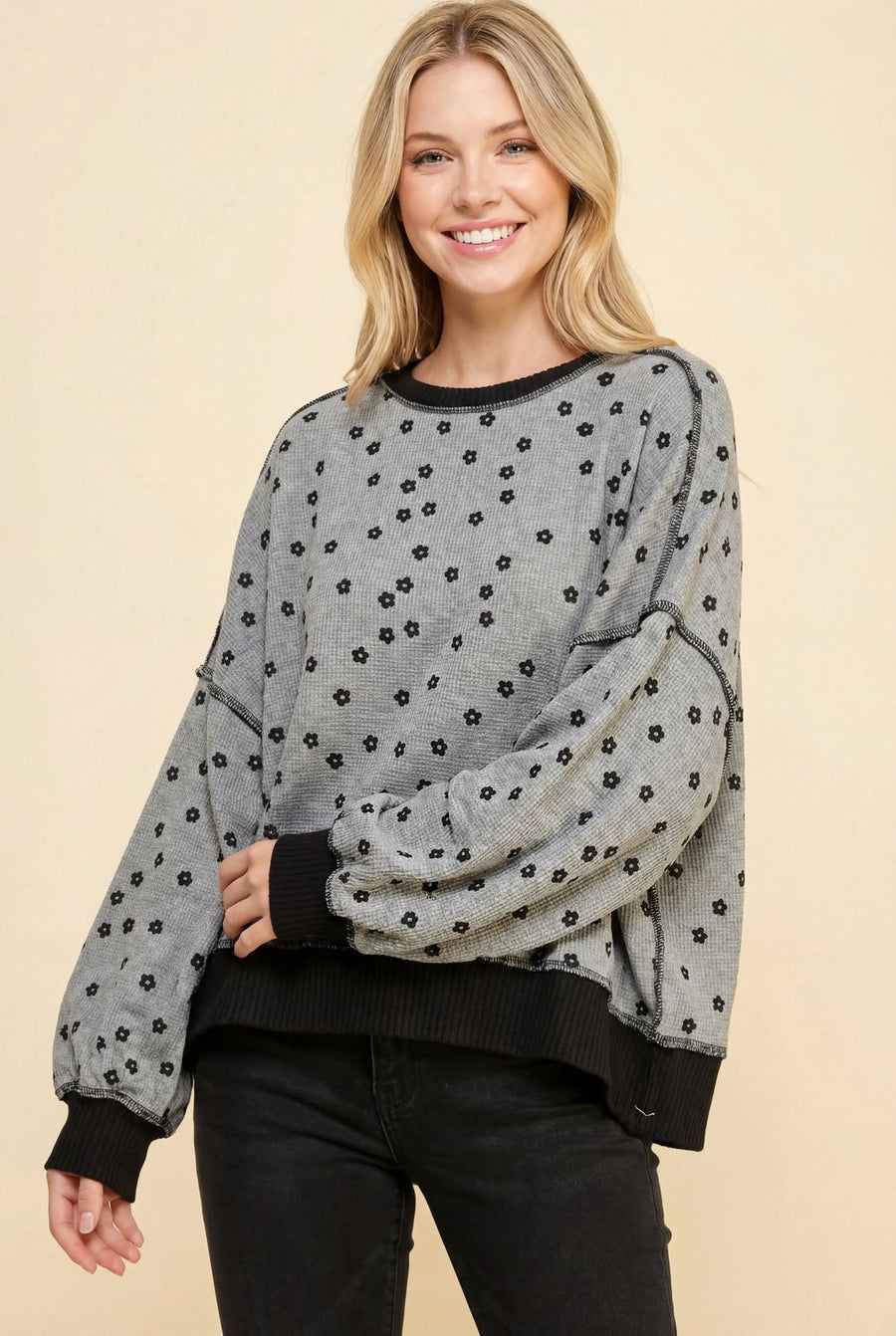 A woman wearing a black floral waffle knit sweatshirt with a relaxed fit and color-block design.