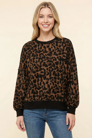 A brown leopard print crew neck sweatshirt with a relaxed fit, worn by a model with jeans.