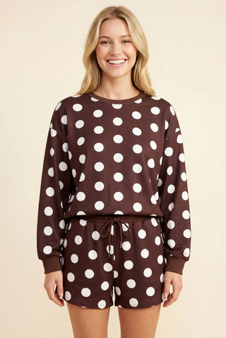 Model wearing a brown and white polka dot sweatshirt and shorts set with long sleeves and elastic waistband.
