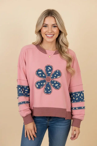 A rose oversized sweatshirt with daisy applique design and raw edge detailing, worn by a model.