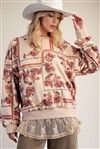 A woman wearing a khaki pullover with a floral print, featuring long sleeves and a relaxed fit.