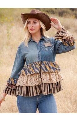 A woman wearing a vintage boho denim tunic with a patchwork yoke and tiered layers in sand.