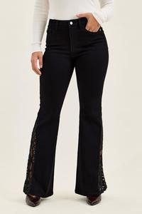 Black jeans with lace hem detail worn by a person in a white top.