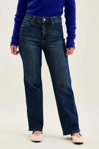 Woman wearing dark indigo straight leg jeans with a fitted blue top.