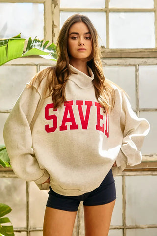 Ash grey sweatshirt with red 'Saved' embroidery and a mock neck worn by a model.
