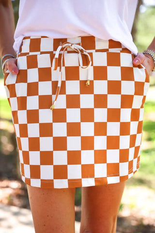 Orange checkered skort with a drawstring waist, paired with a white top.