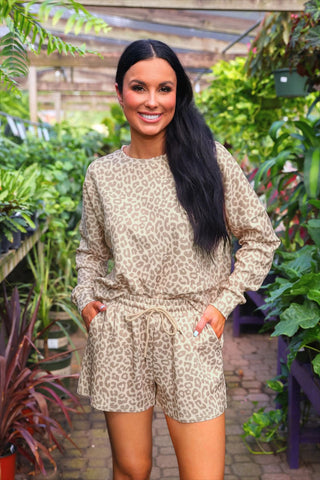 Woman wearing a leopard print pullover and shorts set in a garden setting.