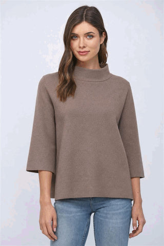 A woman wearing a dusty brown mock neck sweater with bell sleeves.