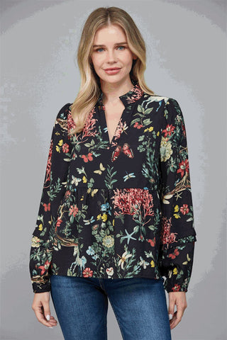 A woman wearing a black top with a multicolor floral print, featuring a high neck band and V-neck.