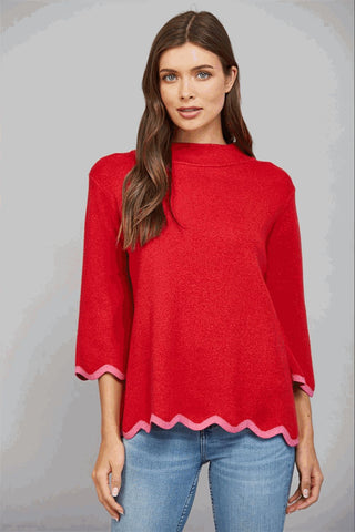 Red sweater with a pink scalloped hem and mock neck, worn by a model with three-quarter sleeves.