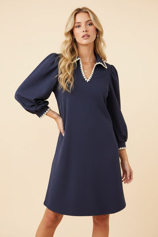 A navy mini shift dress with a V-neckline and long puff sleeves featuring trim details.