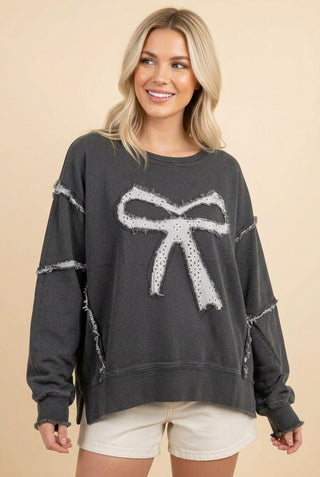 Charcoal denim-style pullover sweatshirt with a large bow design, worn by a model.