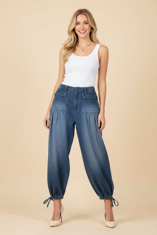 Model wearing dark denim barrel leg pants with an elastic waistband and drawstring cuffs.