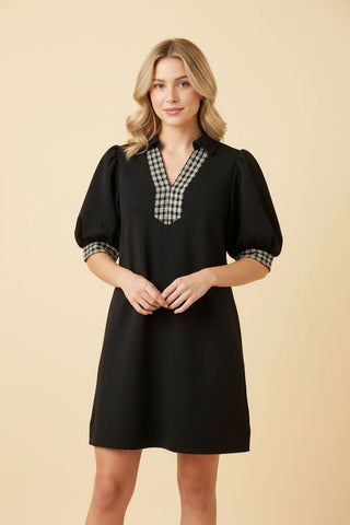 A black shift dress with short sleeves and a V-neckline featuring a checkered trim.