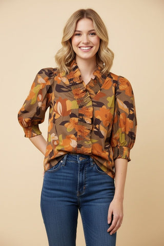 Mocha blouse with abstract floral print, ruffled neckline, and puff sleeves worn by a model.