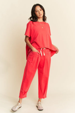 A model wearing a red pleated top and pants set with a relaxed fit.