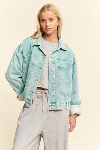 Studded acid-wash denim jacket in washed sea bass, oversized fit, worn by a model with rolled sleeves.