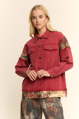 A wine-colored stone-washed denim jacket with floral tapestry panels, worn by a model.