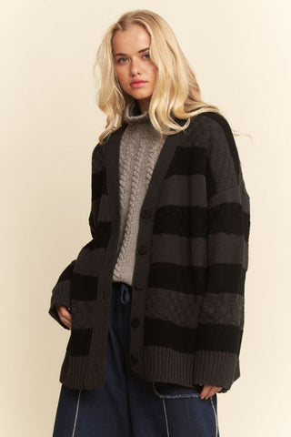 An oversized cardigan with a textured stripe design in black charcoal, featuring a button-front closure.