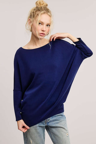Navy dolman top with relaxed fit and long sleeves, worn by a model with light hair in a casual pose.