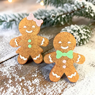 Two gingerbread-shaped vent clips and magnets with decorative bows and buttons on a snowy background.