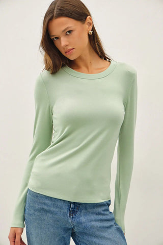 Model wearing a mint long sleeve knit top with a round neckline.