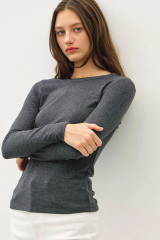 A woman wearing a dark charcoal long sleeve knit top with a round neck.