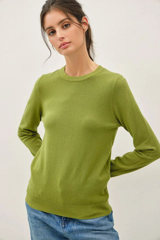 A woman wearing a matcha-colored crew neck sweater with long sleeves.