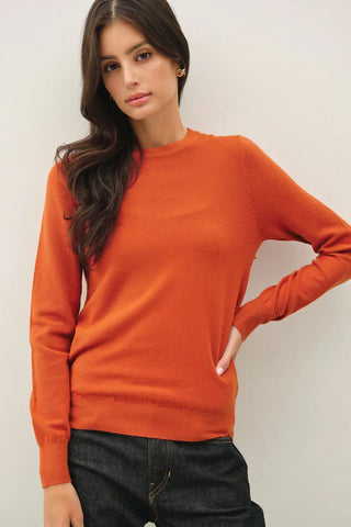 Soft knit crew neck sweater in rust color, worn by a model.