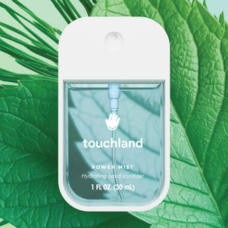 Touchland Frosted Mint Power Mist Hydrating Hand Sanitizer in a 1 fl oz clear bottle with mint leaves in the background.