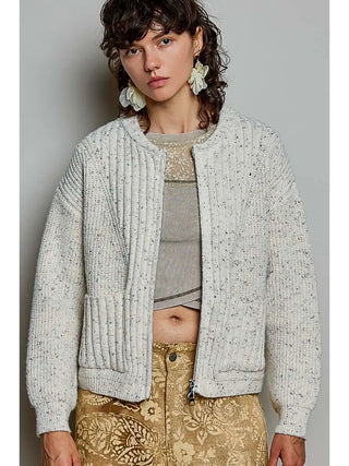 A woman wearing an oatmeal-colored textured rib knit cardigan with a mock neck and two-way zip.