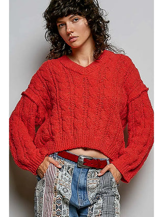 A vibrant orange semi-cropped sweater with a V-neckline, worn by a model.