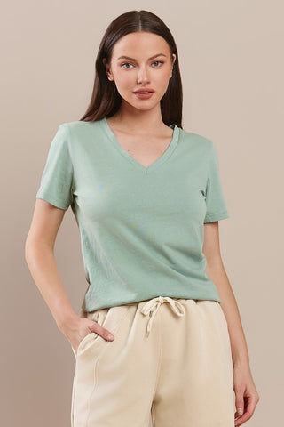 A woman wearing a sage V-neck cotton T-shirt with short sleeves.