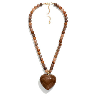 A brown stone beaded necklace with an acrylic heart pendant and gold accents.