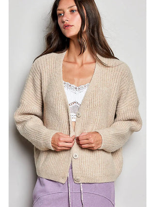 Woman wearing a long sleeve V-neck almond cardigan with a button-down front.