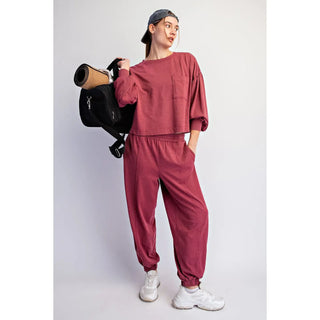 A woman wearing a crimson mineral washed jogger set with a long-sleeve top and elastic waistband pants.