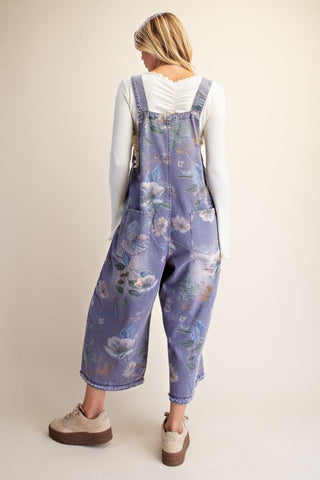 Back view of flower printed washed denim overalls featuring a floral pattern and relaxed fit.